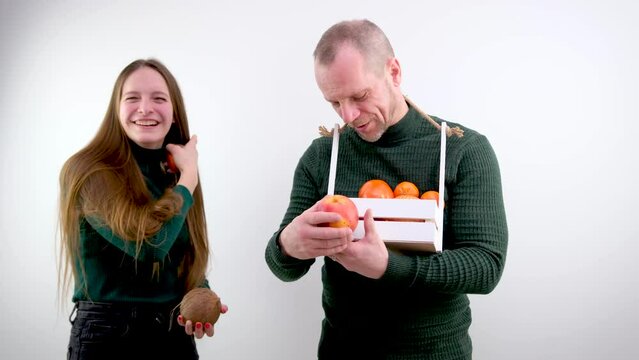 comic photo different size of breasts one breast is larger than the other is smaller girl holding fruit tangerine and cocoas smiling man next to a basket in form of box looks at teenage joke instead