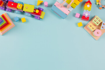 Baby kids toys background. Wooden train, colorful sustainable educational toys on light blue background. Montessori, eco-friendly toys for children. Top view, flat lay