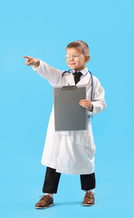 Cute little doctor with clipboard pointing at something on blue background