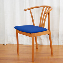 Mid-century modern minimalist wooden chair with a blue seat. 1960s wishbone-style chair. Angle view...