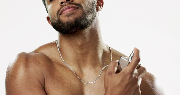 Beauty, cosmetics and man with cologne, fragrance and wellness against a grey studio background. Latino guy, male and perfume for aroma, fresh scent and confidence with spray, self care and hygiene