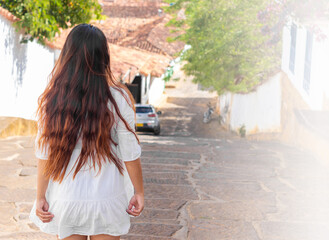Naklejka premium beautiful woman from behind with a white dress and long hair in a town in Colombia
