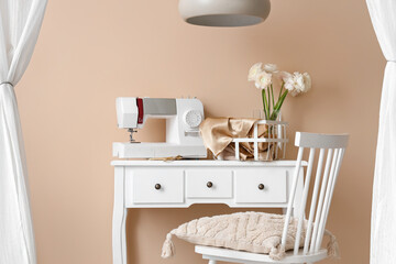 Tailor's workplace with sewing machine near beige wall in workshop