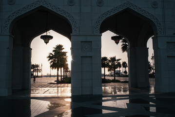 Obraz premium Presidential Palace, Palace of Qasr al-Watan (the Palace of the nation) outside, symmetry columns and palm silhouette at sunset, Abu Dhabi city in Arab Emirates, United Arab Emirates