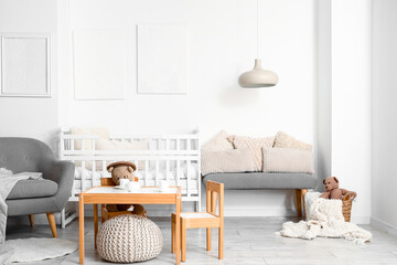 Interior of light children's bedroom with baby crib, table and chairs