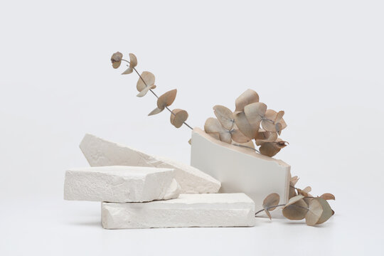 Stack stones platform podium and eucalyptus leaf twig on gray light copy spase background. Minimal empty display product presentation scene.
