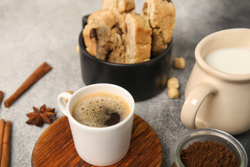 Delicious biscotti cookies, pitcher with milk and cup of coffee on grey grunge background