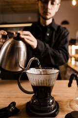 Clever coffee dripper and pour over filter with ground coffee in the funnel in focus. Drip filter coffee brewing. Pour over alternative method of pouring water over coffee beans contained in filter.