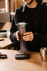 Barista is brewing aeropress before pouring coffee drops trought aeropress to pot. Alternative scandinavian coffee brewing method. Aeropress coffee.