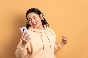 fun brazilian woman looking at mobile cell phone screen in beige colors. app, social media, addiction, network concept.