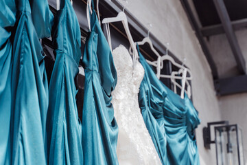 Bridesmaid's dress, white wedding dress hanging next to blue bridesmaid dresses