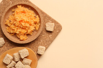 Plate of body scrub and cane sugar on color background