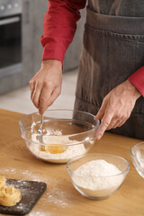 Obraz na płótnie Canvas Man making dough for pasta at table in kitchen, closeup