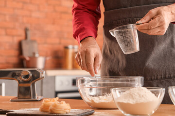 Fototapeta na wymiar Man making dough for pasta at table in kitchen, closeup