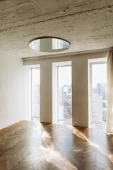 room with large windows in a duplex apartment. room with parquet floor and concrete ceiling with round mirror.