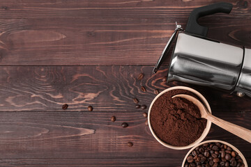 Bowls of coffee powder, beans and maker on dark wooden background