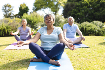 Happy diverse group of senior friends practicing yoga and meditating in garden