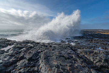 Black rocks on the coast of Iceland with big waves