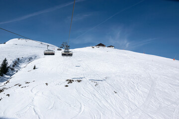 Fototapeta na wymiar Pass Thurn, Austria - Chair lift for skiers goes up the snowy hill in winter.
