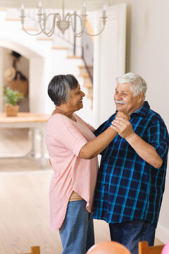 Happy diverse senior people holding hands and dancing at home