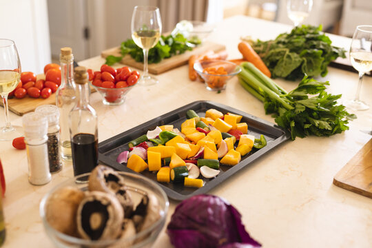 Fresh vegetables and seasonings on table in kitchen with bottle and glasses of white wine