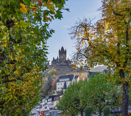 Naklejka premium Roadside shot of Cochem town and castle through trees in the afternoon during colourful autumn season in Cochem-Zell district, Germany
