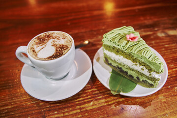 slice of matcha tea cake with a cup of latte coffee