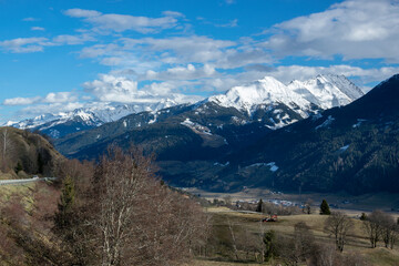 Snowy mountain peaks and valleys with trees and meadows in winter in Austria.