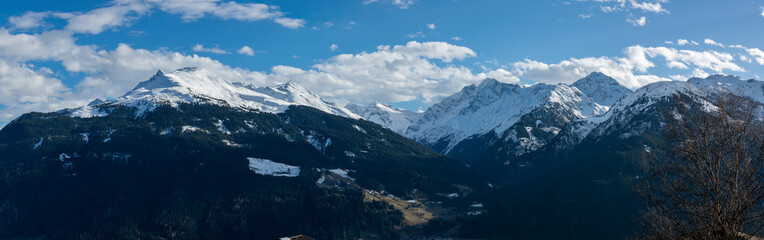 Fototapeta na wymiar Panorama of snowy mountain peaks above a valley with forests in winter in the Austrian Alps.