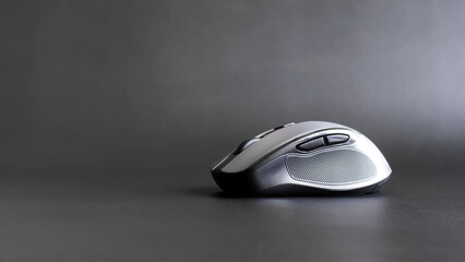 Modern gray wireless computer mouse on a gray textured background. Side view. Copy space.