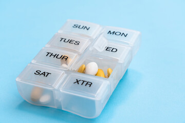 Pill organizer with variety of pills and supplement. Weekly Pill container on blue background with copy space