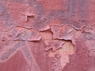 A fragment of the wall of a tenement house with falling off fragments of old, cracked paint forming abstract abstract patterns, Madrid, Spain.