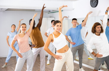 Fototapeta premium Active women and men dancing synchronous group choreography in dance hall