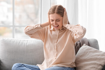 Angry young woman suffering from loud noise at home - obrazy, fototapety, plakaty