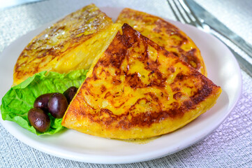 Obraz na płótnie Canvas Spanish vegetarian food, portion of homemade tasty potato omelette tortilla de patatas with onion served in morning sunlights