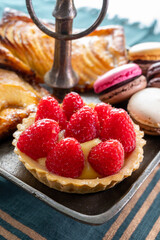 High tea with sweet baked tart with ripe red raspberry, apple cake with cinnamon and fresh French macarons biscuits