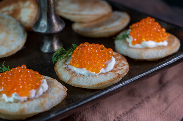 Tasty appetizer for dinner, small pancakes bliny with red fish caviar and sour cream