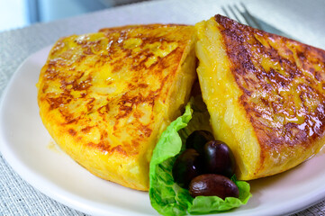 Spanish vegetarian food, portion of homemade tasty potato omelette tortilla de patatas with onion served in morning sunlights