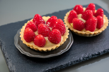 Artisanal baked small tart with cream and fresh ripe red raspberry