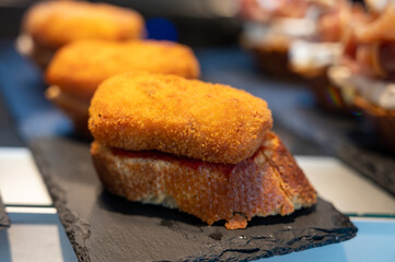 Typical mini burger snack of Basque Country, pinchos or pinxtos, small piece of bread with different toppings, served in bar in San-Sebastian, Spain