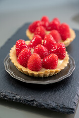 Artisanal baked small tart with cream and fresh ripe red raspberry