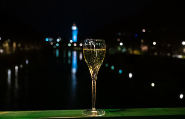 Fototapeta na wymiar Tasting of french sparkling white wine with bubbles champagne outdoor at night with view on Marne river and lights of Epernay city in winter
