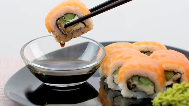 Salmon sushi set on a white plate. Sushi roll with red fish, salmon, red caviar. Roll with fresh salmon, soft avocado, with shrimp and crab and cream cheese under a wide layer of massago caviar