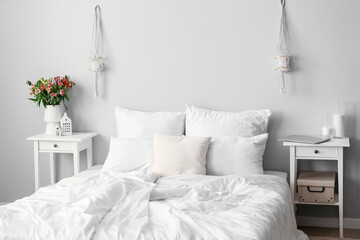 Stylish interior of light bedroom with alstroemeria flowers