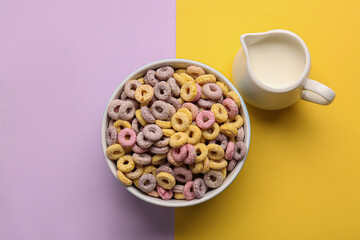 Obraz na płótnie Canvas Bowl of cereal rings and pitcher with milk on colorful background