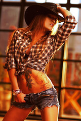 Young woman cowboy at sunset light, tattoo on body
