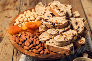 Obraz na płótnie Canvas Board with delicious biscotti cookies, dried apricots and nuts on wooden background