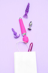Shopping bag with sex toys on lilac background