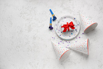 Composition with party hats, whistles and gift box on light background