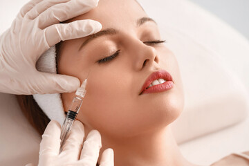 Young woman receiving filler injection  in beauty salon